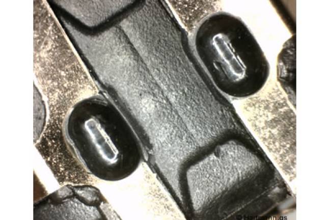 Ein Blech-Stanzteil wird durch einen heißverstemmten Pin in seiner Position fixiert.